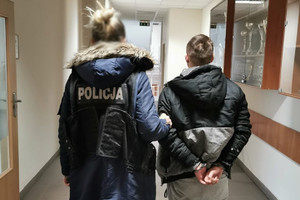 policjantka trzyma zatrzymanego skutego kajdankami