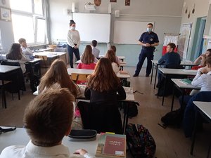 Policjanci i uczniowie podczas zajęć w klasie szkolnej. Uczniowie siedzą w ławkach.