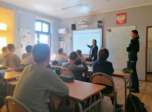 Policjanci i uczniowie podczas zajęć w klasie szkolnej.