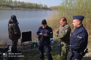 policjanci i strażnik leśny legitymują wędkarza nad wodą