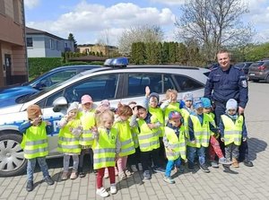 Dzieci wraz z policjantem stoją przy radiowozie.