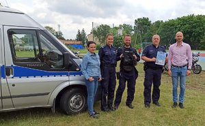 trzej policjanci, kobieta i mężczyzna stoją obok siebie obok radiowozu