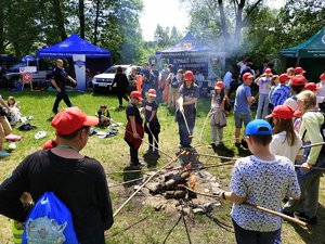 dzieci stoją przy ognisku i pieką kiełbaski na kijkach