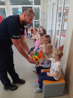 Policjant rozdaje dzieciom odblaski.