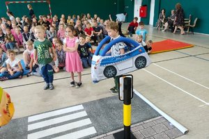 dziecko ma ubrany na sobie autochodzik i stoi przed przejściem dla pieszych