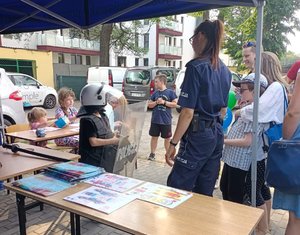 Policjantka i dzieci stoją pod namiotem policyjnym.