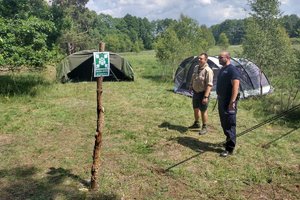 policjant stoi razem z harcerzem koło namiotów i punktu zbiórki