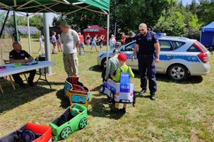 chłopiec ma założony autochodzik, obok stoi policjant