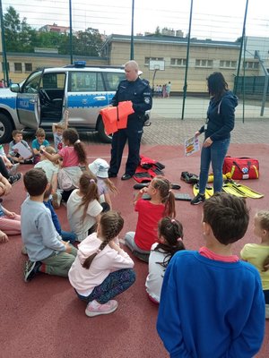 Policjant i dzieci podczas pogadanki na boisku.