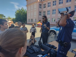 Policjanci prezentują sprzęt policyjny leżący na stole przed uczniami.