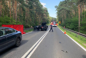 policjant przechodzi obok rozbitego pojazdu z aparatem fotograficznym