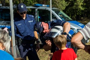 Policjanci przymierzają dzieciom kaski policyjne.