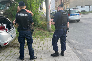 dwaj umundurowani policjanci kontrolują pojazd