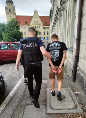 Policjant prowadzi zatrzymanego.