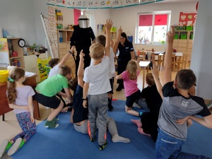 Policjant ma założone umundurowanie bojowe. przed nim stoją dzieci.