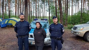 Policjanci oraz kobieta stoją w lesie.