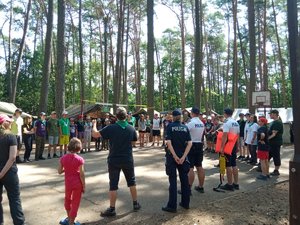 Obozowicze i policjanci stoją w kole podczas prelekcji.