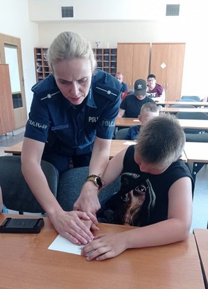 Policjantka i chłopiec podczas wykonywania odbitki dłoni.