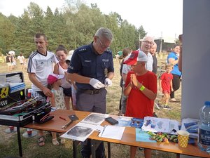 Dzieci i dorośli przy stoisku technika kryminalistycznego.