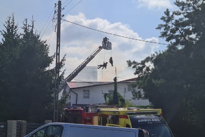 strażacy na wysięgniku spuszczają się po linie na dach budynku