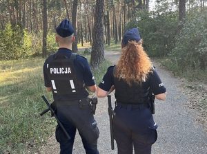 Policjanci podczas patrolu w terenie zielonym.