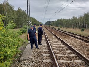 Policjant i strażnik ochrony kolei na torowisku.