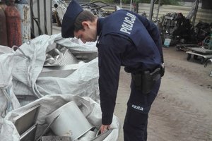 policjant nachyla się nad workiem z metalowymi elementami