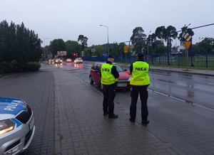 Policjanci stoją przed kontrolowanym pojazdem.