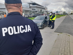 Policjant, a w tle kontrolowane przez policjantów ruchu drogowego auto.