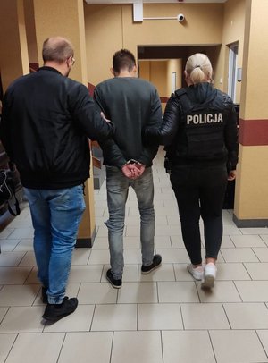 Policjanci prowadzą zatrzymanego korytarzem prokuratury.