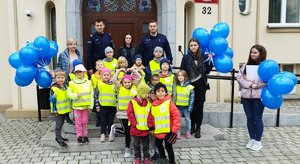 Wspólne zdjęcie policjantów, dzieci i ich opiekunów na schodach Komendy Miejskiej Policji w Bydgoszczy.