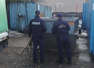 Policjant i sokista stoją przy kontenerze.