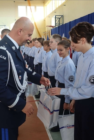 Komendant Wojewódzki Policji w Bydgoszczy wręcza uczniom upominek