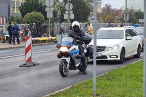 policjant siedzi na policyjnym motocyklu na drodze