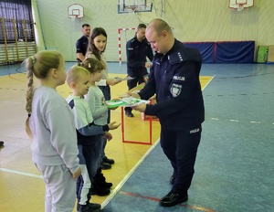 zastępca komendanta komisariatu wręcza dzieciom nagrody