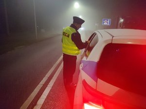 policjant kontroluje trzeźwość kierowcy samochodu osobowego