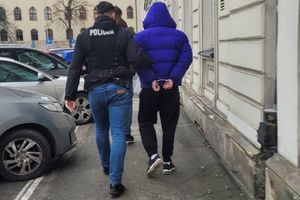 nieumundurowani policjanci prowadzą zatrzymanego skutego kajdankami