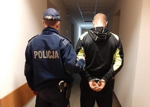 policjant prowadzi zatrzymanego