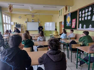 Policjant i uczniowie podczas zajęć w klasie szkolnej.