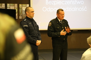 Zdjęcie przedstawia policjanta i strażnika miejskiego podczas przemowy.