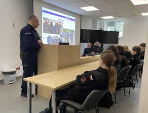 policjant i uczniowie podczas spotkania oglądają prezentację multimedialną