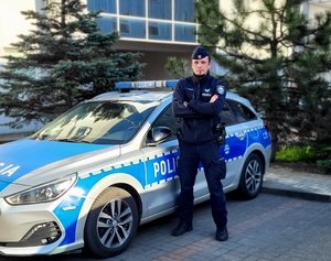 policjant stoi przy radiowozie