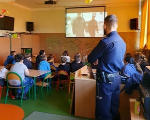 UCZNIOWIE I POLICJANT PODCZAS OGLĄDANIA SPOTU PROFILAKTYCZNEGO