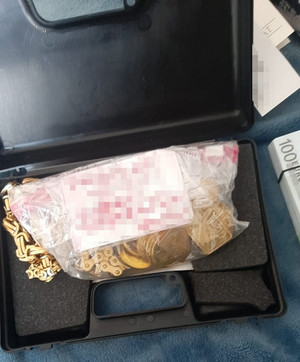 złoto w worku foliowym leżące w plastikowej walizce, obok częściowo widoczny plik banknotów
