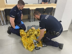 policjanci przykrywają ofiarę kocem termicznym