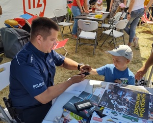 policjant i dziecko przy stoisku profilaktycznym