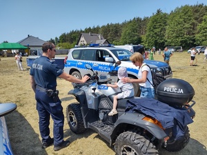 dziecko siedzi na policyjnym quadzie, przy nim stoi kobieta oraz policjant