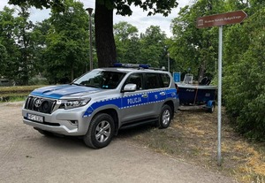 radiowóz z policyjną łodzią na tle drzew