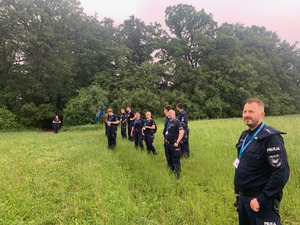 policjanci podczas marszu przez tereny trawiaste