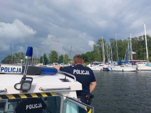 policjant na łodzi, w tle zacumowane jachty
